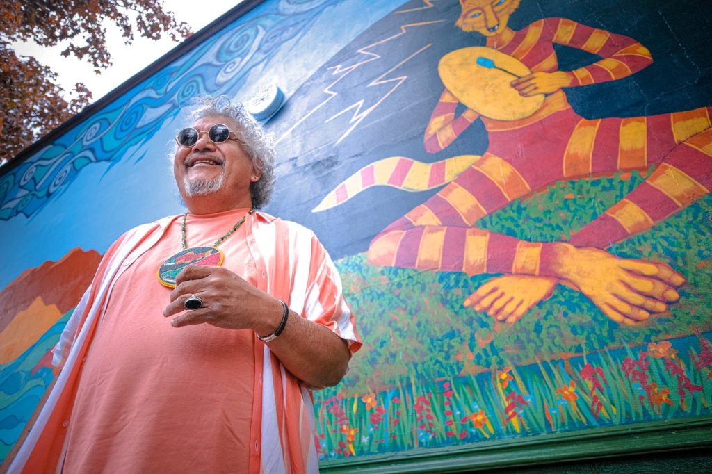 Ric Gendron smiles in front of finished mural